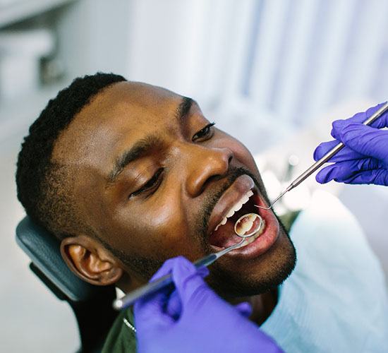 A young man receives a dental checkup during a regular appointment with his dentist