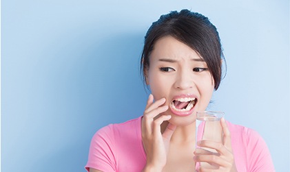 Woman with cavity holding glass of water