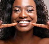 Smiling woman pointing to her white teeth