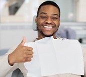 Man smiling while giving thumbs up in treatment chair