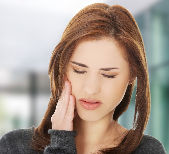 woman holding cheek in pain