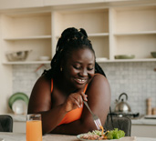 Woman smiling while eating in kitchen