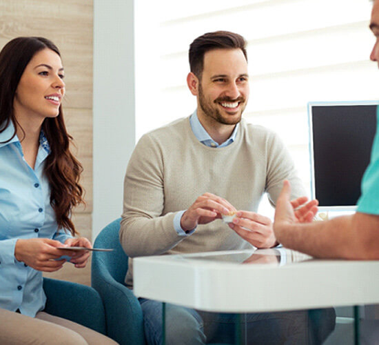 dentist and couple talking in dental office