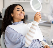 patient smiling at reflection in handheld mirror