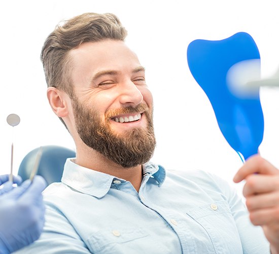 man checking smile in blue mirror