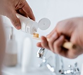 Patient putting toothpaste on toothbrush