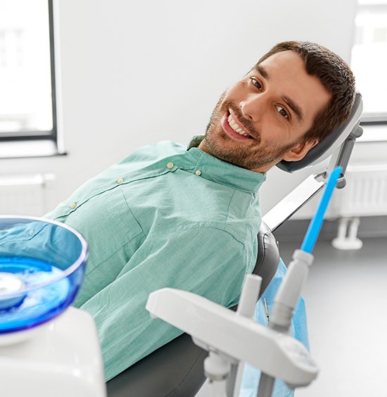 man in green shirt laying back in exam chair