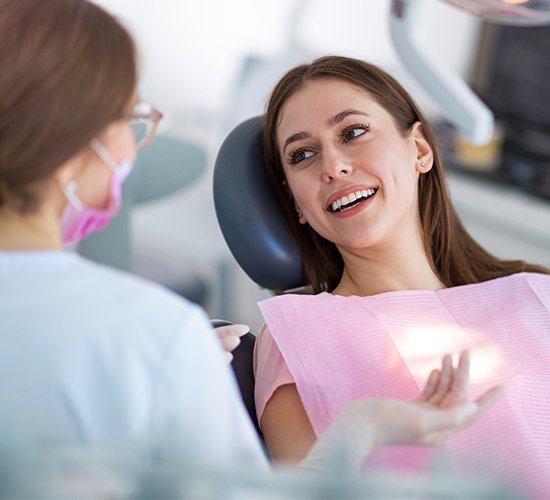 woman talking to dentist in exam chair