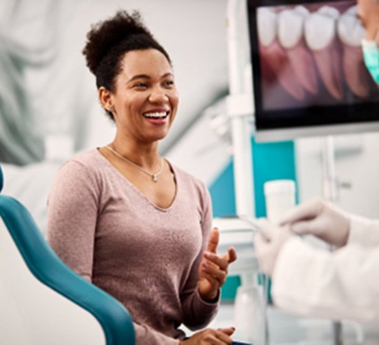 Woman smiling while talking to cosmetic dentist about veneers