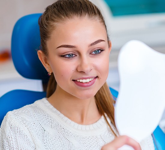 girl checking smile in white mirror