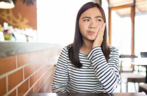 Concerned woman hand to face wonders should she see Rockledge emergency dentist