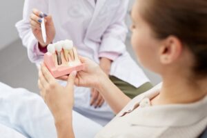 A dentist showing their patient a model of a dental implant. 